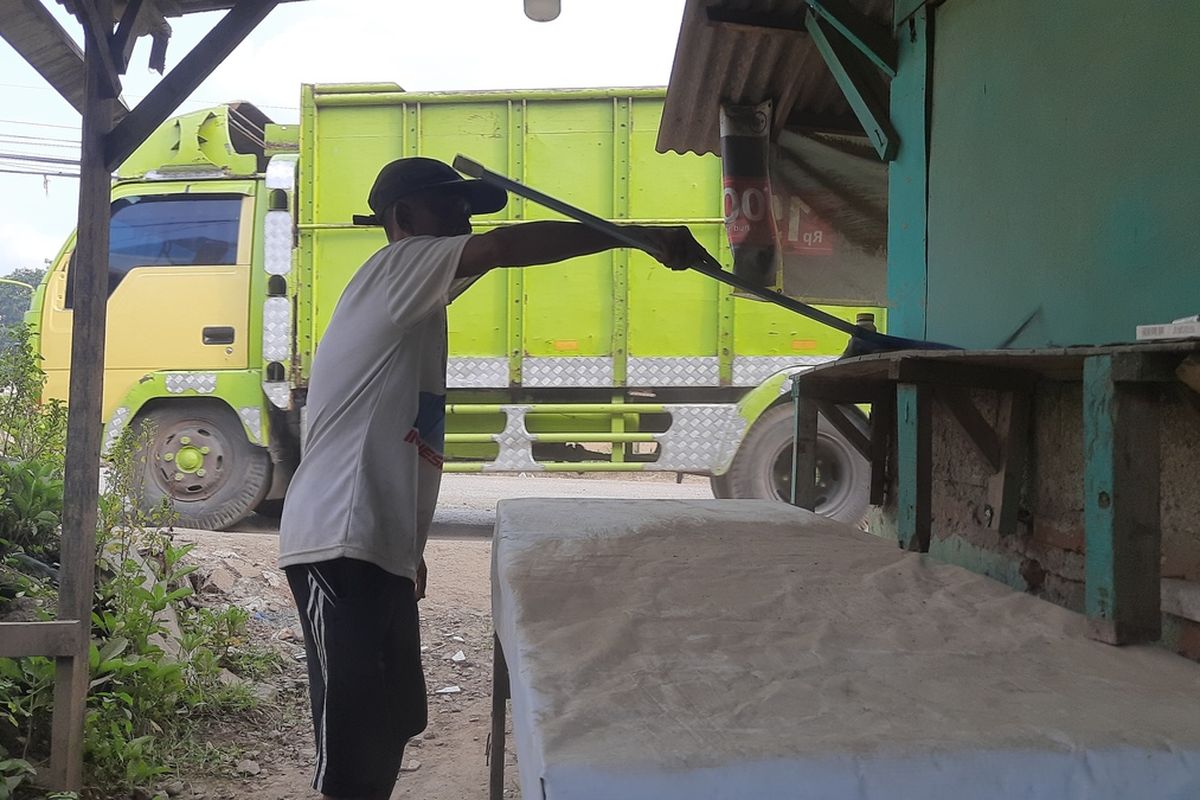 Subur (57), warga Parung Panjang sedang menyapu warung dan rumahnya yang dipenuhi debu dari truk tambang yang melintas di Jalan Sudamanik, Parung Panjang, Kabupaten Bogor, Jawa Barat, Rabu (8/1/2025).