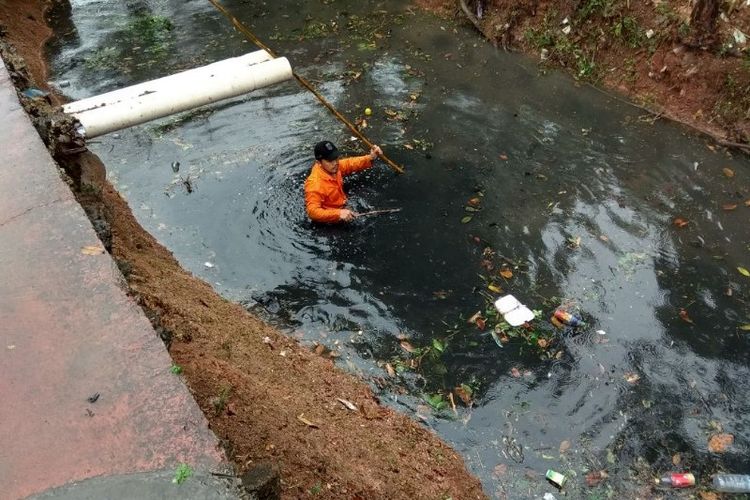 Petugas Pasukan Biru dari Dinas Tata Air membersihkan saluran air di Malaka Sari, Duren Sawit, Jakarta Timur pada Senin (25/6/2018). 