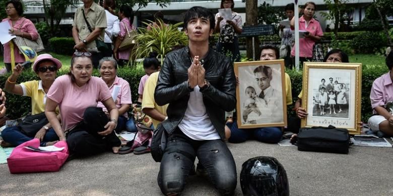Seroang pria berlutut dan berdoa di depan RS Siriraj, Bangkok tempat Raja Bhumibol Adulyadej dirawat, Kamis (13/10/2016).