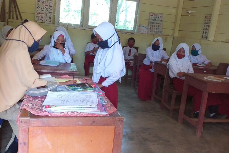 Anak-anak Suku Talang Mamak satu persatu menyerahkan dan menerima tugas sekolah dari gurunya di SDN 028 Desa Talang Sungai Limau, Kecamatan Rakit Kulim, Kabupaten Inhu, Riau, Senin (2/11/2020). Murid sekolah belajar di tengah pandemi Covid-19 dengan sistem antar jemput tugas ke sekolahnya.