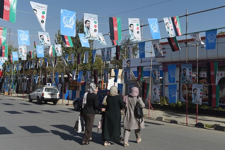 Warga Afghanistan berjalan di bawah spanduk kandidat anggota parlemen jelang dilangsungkannya pemilihan yang akan digelar pada 20 Oktober mendatang.