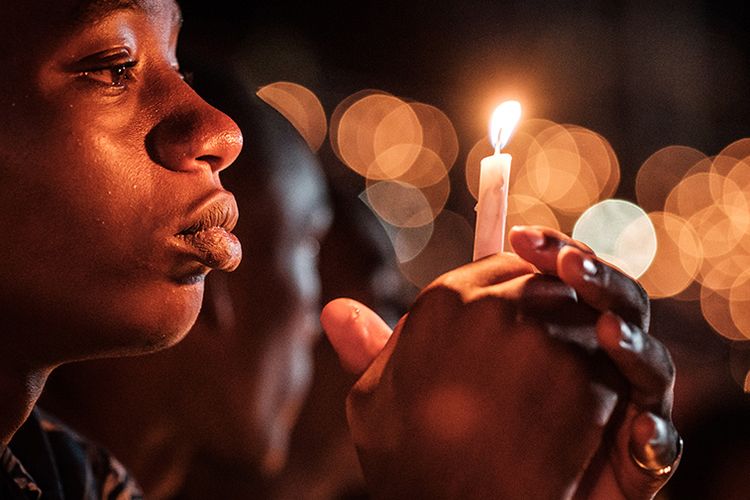 Seorang warga memegang lilin dan mengikuti doa bersama dalam malam peringatan 25 tahun genosida Rwanda di Stadion Amahoro, Kigali, Rwanda, Minggu (7/4/2019). Seperempat abad setelah sejarah kelam itu, kini perekonomian Rwanda sudah jauh membaik dan pada 2016 ditetapkan menjadi negeri kedua terbaik di Afrika sebagai tujuan bisnis.