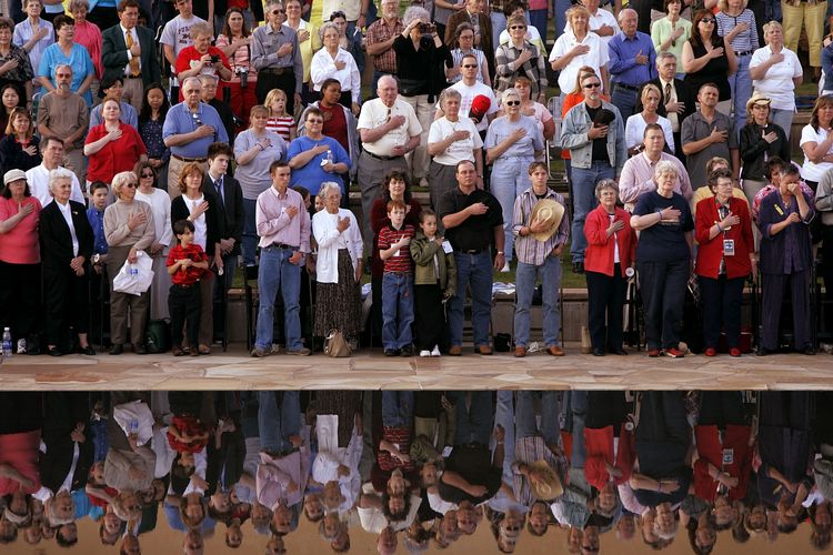 Attendees place their hands over their hearts during the playing of the US national anthem prior to a candlelight vigil at the Oklahoma City National Memorial in memory of the 168 victims killed in 1995 as a result of the bombing of the Alfred P. Murrah Federal Building 17 April, 2005 in Oklahoma City, Oklahoma.  The 10th anniversary of the bombing falls on 19 April.  (Win McNamee/Getty Images/AFP) FOR NEWSPAPER AND TV USE ONLY (Photo by WIN MCNAMEE / Getty Images North America / Getty Images via AFP)