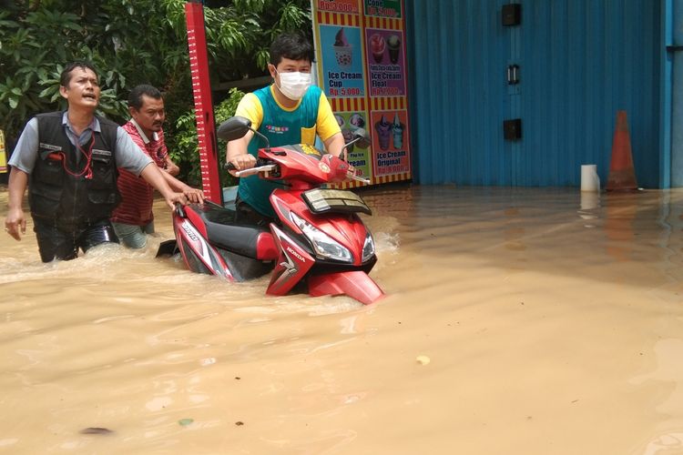 Warga Perum Karaba 1, Desa Wadas, Kecamatan Telukjambe Timur tengih melintasi banjir yang merendam perumahna mereka, Sabtu (20/2/2021).