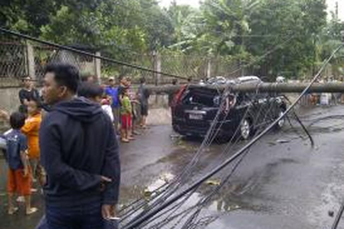 Akibat hujan disertai angin kencang, sebuah tiang listrik di Jalan Raya Kebagusan, Jakarta Selatan, roboh dan menimpa sebuah mobil Nissan X-Trail, Jumat (25/10/2013)