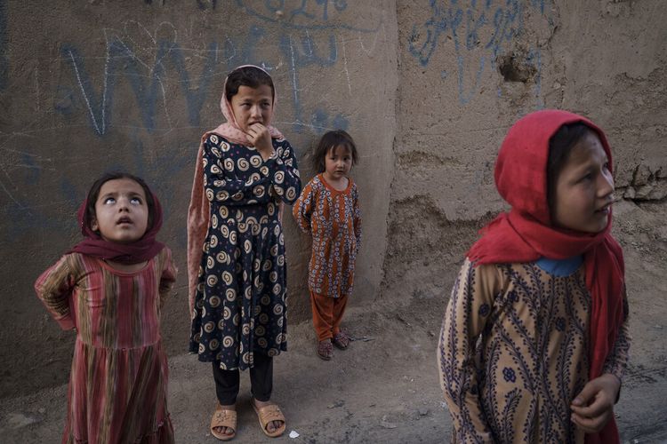 Gadis-gadis Afghanistan melihat ke atas dan mendengarkan ketika seorang tetangga menjelaskan ketika dua pria jatuh dari C-17 Angkatan Udara AS yang lepas landas dari Bandara Internasional Kabul pada 16 Agustus dan mendarat di atap rumahnya di Kabul, Afghanistan, Jumat, 17 September , 2021. 