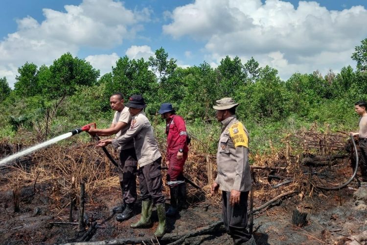 Petugas kepolisian memadamkan api karhutla di Kelurahan Air Hitam, Kecamatan Payung Sekaki, Kota Pekanbaru, Riau, Rabu (21/6/2023).