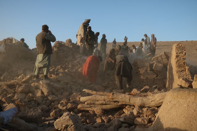Warga Afghanistan membersihkan puing-puing dari rumah yang rusak setelah gempa bumi di desa Sarbuland, distrik Zendeh Jan, provinsi Herat, pada 7 Oktober 2023. Gempa di Afghanistan barat kali ini dilaporkan menewaskan 120 orang.