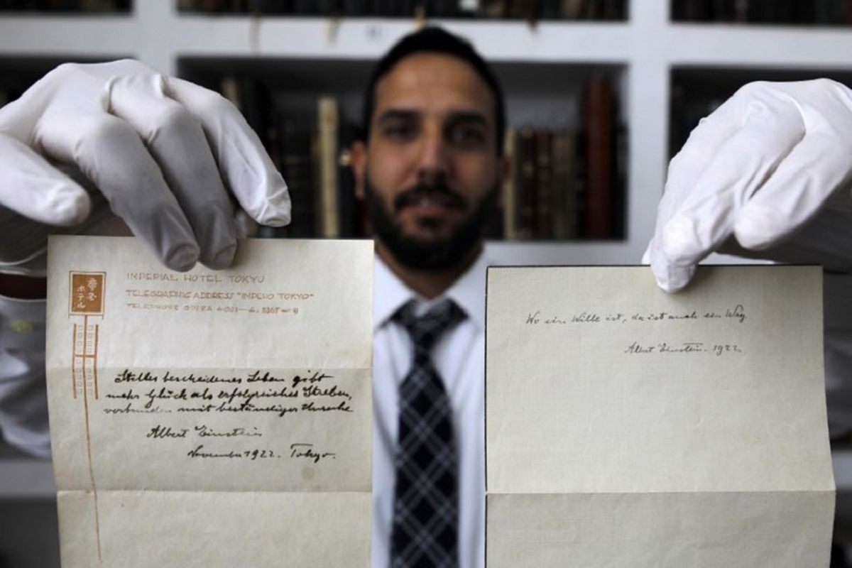 A picture taken on October 19, 2017, shows Gal Wiener, owner and manager of the Winners auction house in Jerusalem, displays two notes written by Albert Einstein, in 1922, on hotel stationary from the Imperial Hotel in Tokyo Japan. 
A note that Albert Einstein gave to a courier in Tokyo, briefly describing his theory on happy living, has surfaced after 95 years and is up for auction in Jerusalem. / AFP PHOTO / MENAHEM KAHANA