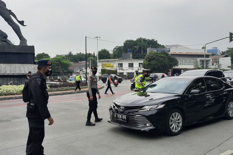 Petugas memberhentikan pengendara yang melanggar aturan ganjil-genap di Jalan Sudirman, Jumat (13/8/2021).