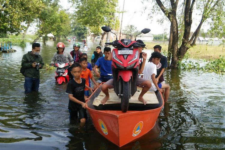 Hindari mogok, sepeda motor dibantu dengan perahu saat melintas di Desa Morowudi, Kecamatan Cerme, Gresik, Kamis (2/5/2019).