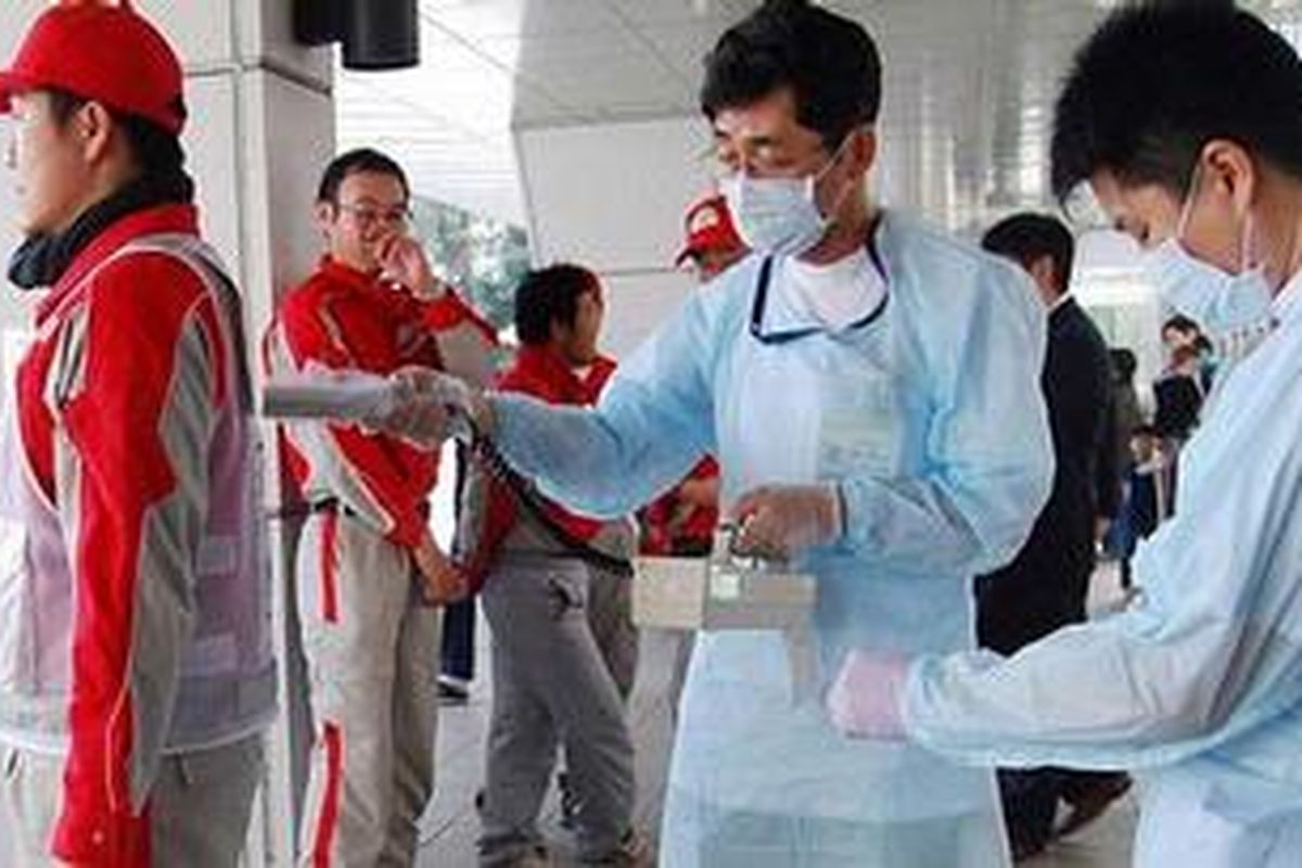 Seorang staf Palang Merah, berpakain warna merah, dipindai guna memeriksa adanya radiasi setelah kembali dari Fukushima ke rumah sakit di Nagahama, Prefektur Shiga