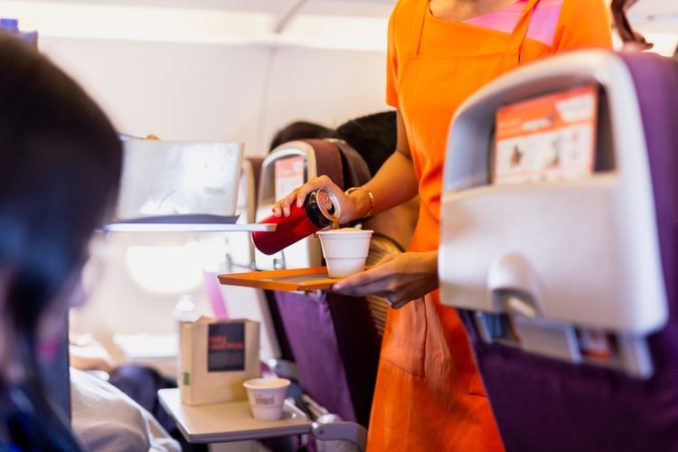 Ilustrasi pramugari menyajikan minuman di dalam pesawat.