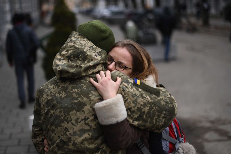 Seorang tentara Ukraina memeluk rekannya di sebelah pangkalan militer tempat penduduk mengantre untuk bergabung dengan tentara, di Lviv, Rabu (2/3/2022). Rusia meningkatkan kampanye pengeboman dan serangan rudal di kota-kota Ukraina.