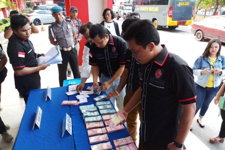 Salah seorang tim penyidik Saber Pungli Polresta Barelang sedang menyusun sejumlah uang yang merupakan barang bukti dari dugaan kasus pungli PPDB yang dilakukan di SMA Negeri 10 Sei Panas, Batam