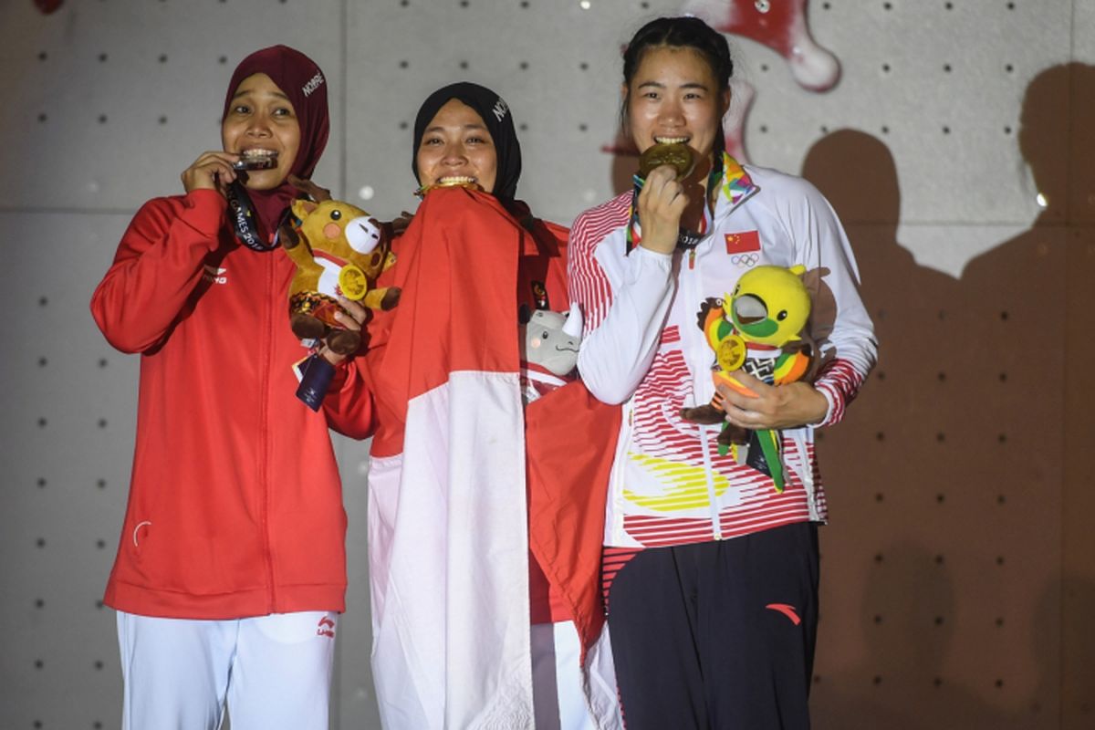 Atlet panjat tebing Indonesia peraih medali emas Aries Susanti Rahayu (tengah), Puji Lestari (kiri) dan atlet panjat tebing Cina He Cuilian (kanan) mengikuti penganugerahan medali seusai final katagori speed putri di Arena Panjat Tebing Jakabaring Sport City, Palembang, Sumatera Selatan, Kamis (23/8). ANTARA FOTO/INASGOC/Hendra Nurdiyansyah/nym/18.