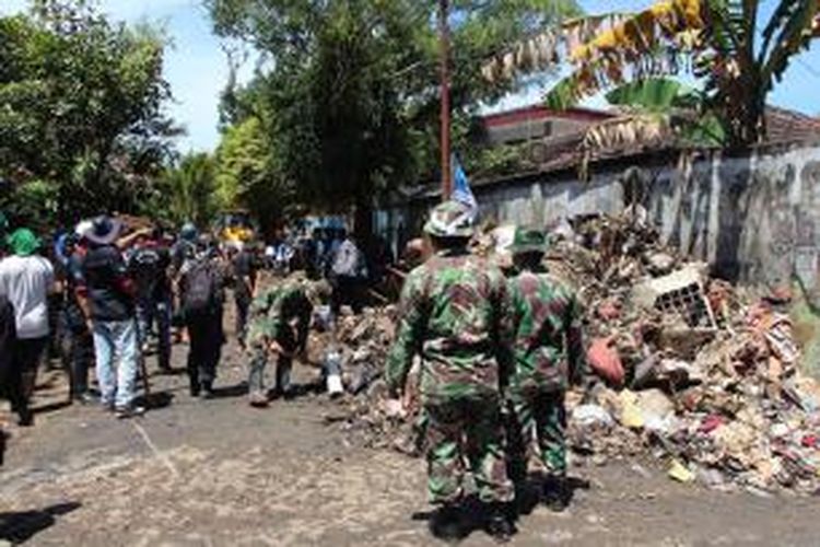 Relawan dan prajurit TNI bahu membahu membantu warga korban banjir bandang di Manado membersihkan lingkungan mereka.