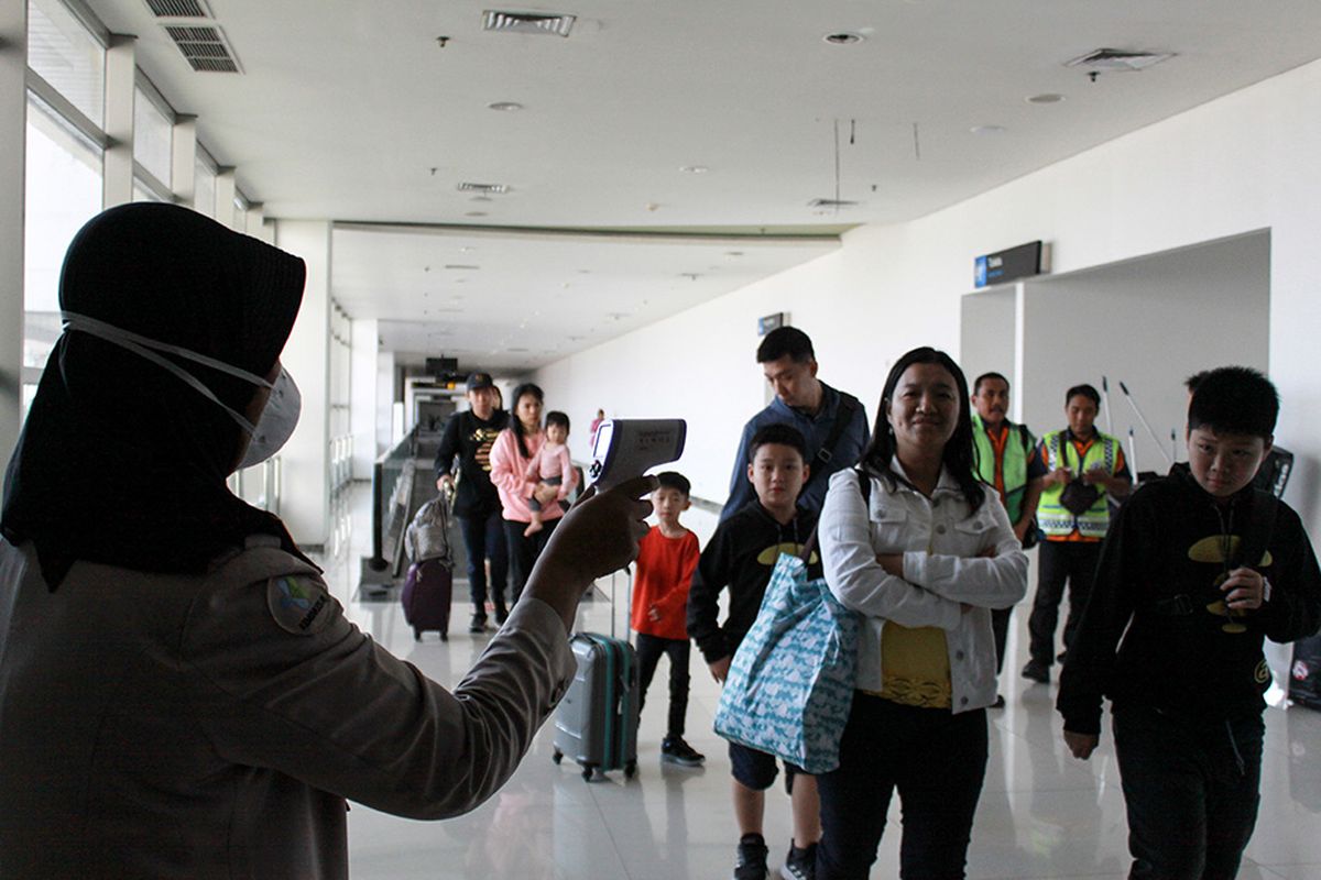 Petugas melakukan pendeteksi suhu tubuh (thermal scanner) saat penumpang pesawat tiba di terminal 2 Bandara Juanda Surabaya, Jawa Timur, Rabu (22/1/2020). 