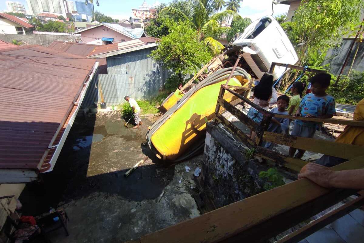 Truk tinja yang baru saja melakukan penyedotan kotoran nyungsep di salah satu rumah warga, isinya tumpah.