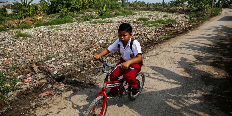 Warga melintas disamping sampah yang didominasi plastik di sepanjang Kali Pisang Batu, Desa Pahlawan Setia, Kecamatan Tarumajaya, Kabupaten Bekasi, Jawa Barat, Selasa (8/1/2019). Sampah yang memenuhi Kali Pisang Batu hingga sepanjang 1,5 kilometer berasal dari Kali Bekasi yang melewati Kota Bekasi. Sampah muncul pasca normalisasi dilakukan pada Desember 2018. Sebelumnya, kali hanya dipenuhi lumpur dan eceng gondok.