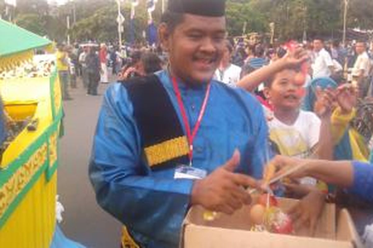 Para penonton Pawai Seni dan Budaya Kreatif saling berusaha mendapatkan telur rebus yang dibagikan peserta pawai dari Riau, Senin (18/8/2014).