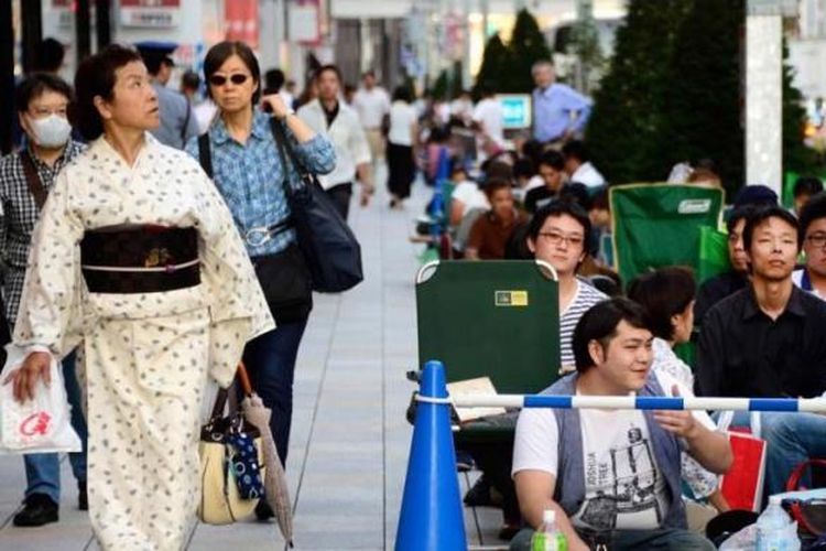 Seorang wanita berkimono berjalan di samping antrean warga di depan Apple Store di Ginza, Tokyo untuk membeli iPhone terbaru, 19 September 2013. Apple resmi memasarkan produk terbaru iPhone 5s dan 5c ke seluruh dunia.