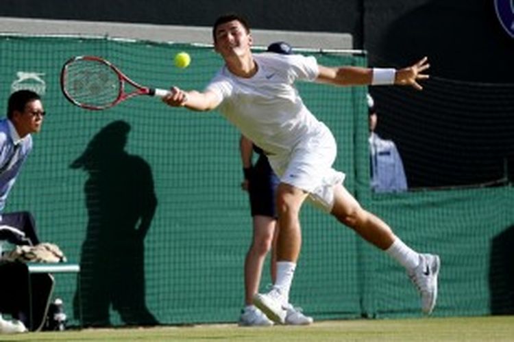 Petenis Australia, Bernard Tomic, mencoba menjangkau bola yang dikirim Tomas Berdych dari Ceko, saat berhadapan di babak keempat turnamen grand slam Wimbledon, Senin (1/7/2013).