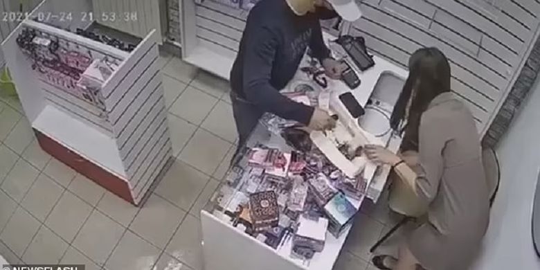 Potongan rekaman video memperlihatkan penjaga toko meraba-raba bagian bawah konternya, sebelum memukulkan mainan seks dildo ke arah perampok di Rusia, pekan lalu.