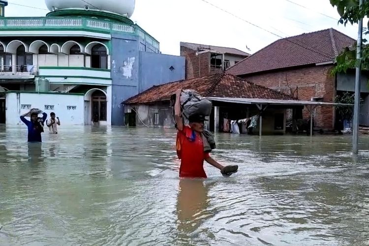 Warga Desa Cangkring, Kecamatan Karanganyar, Kabupaten Demak, melintas banjir, Minggu (17/3/2024) sore. (KOMPAS.COM/NUR ZAIDI)