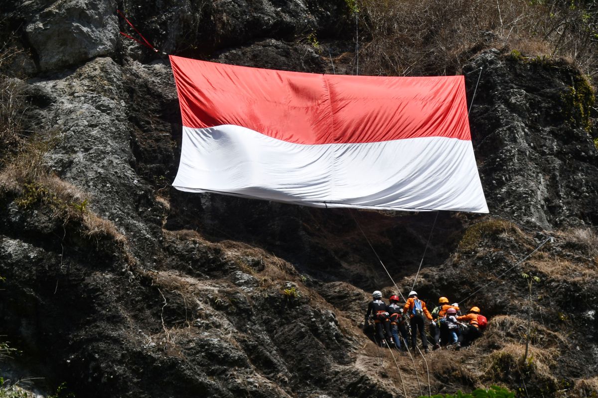 Pegiat panjat tebing membentangkan Bendera Merah Putih berukuran panjang sembilan meter dan lebar enam meter di tebing Kerto Embo, kawasan lereng Gunung Wilis, Kabupaten Madiun, Jawa Timur, Kamis (17/8/2023). Pembentangan bendera Merah Putih pada ketinggian 70 meter serta upacara diikuti 70 peserta dari angota Federasi Panjat Tebing Indonesia (FPTI), mahasiswa pecinta alam (mapala), siswa pecinta alam (sispala), Badan Penanggulangan Bencana Daerah (BPBD), anggota Polri dan masyarakat umum tersebut dalam rangka Peringatan Hari Ulang Tahun ke-78 Proklamasi Kemerdekaan RI.