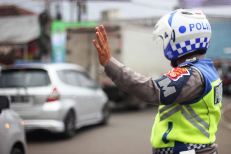 Seorang anggota polantas tengah mengaur arus lalu lintas di bilangan bundaran TUgu Lampu Gentur, Kabupaten Cianjur, Jawa Barat.