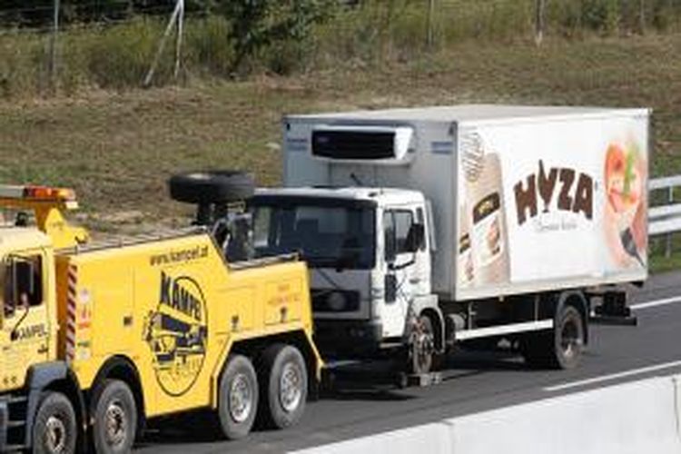 Kepolisian Austria menderek truk barang yang ditemukan berisi puluhan jasad migran Timur Tengah, Kamis (27/8/2015), di tepian sebuah jalan tol di negeri itu.