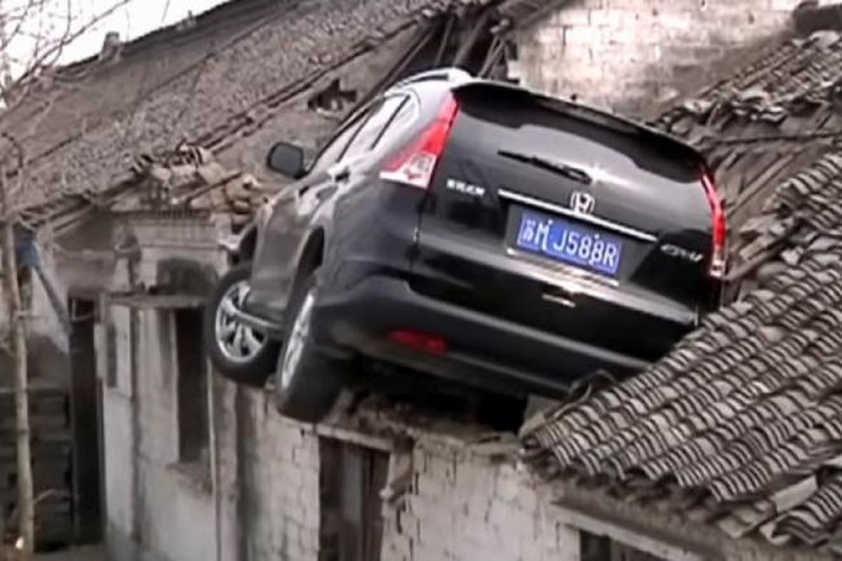 Honda CR-V yang tersangkut di atap rumah di China.