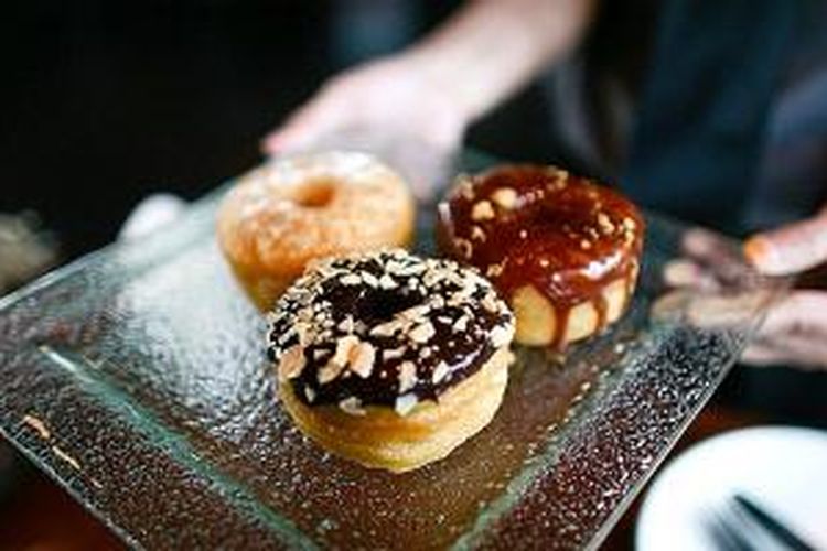 Pramuniaga menyuguhkan kue cronut di Otel Lobby Kitchen and Bar, Epicentrum Kuningan, Jakarta, Sabtu (28/12/2013). Kue itu diminati banyak orang karena sensasi gurih dan renyah saat menggigitnya.