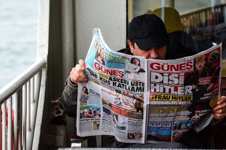 Seorang warga kota Istanbul, Turki sedang membaca edisi terbaru harian Gunes yang memajang wajah Kanselir Jerman Angela Merkel dalam balutan seragam Nazi.