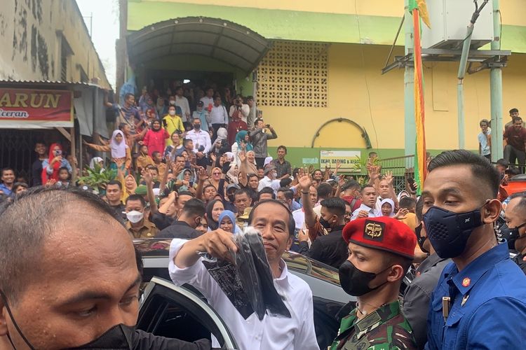 Presiden Jokowi membagikan baju kaos kepada warga di Pasar Bawah di Kota Pekanbaru, Riau, Rabu (4/1/2023).