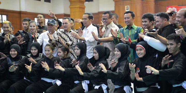 Presiden Joko Widodo (tengah) didampingi Menteri PUPR Basuki Hadimuljono (kelima kiri), Menpora Imam Nahrawi (keempat kanan) dan Ketua Harian Pengurus Besar Ikatan Pencak Silat Indonesia (IPSI) Edhy Prabowo (kelima kanan) berpose dengan atlet dan ofisial pelatnas pencak silat di Padepokan Pencak Silat TMII, Jakarta, Senin (6/8/2018). Presiden optimis atlet pencak silat akan memperoleh lebih dari dua medali emas pada ajang Asian Games 2018.