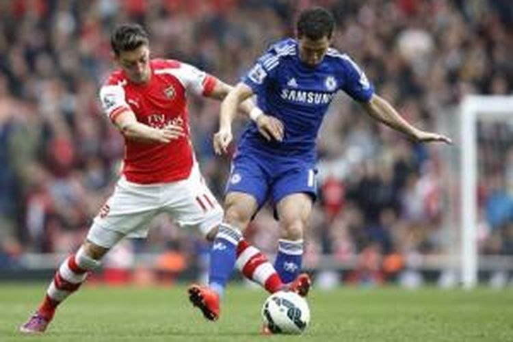 Gelandang Arsenal Mesut Oezil (kiri) berebut bola dengan gelandang Chelsea Eden Hazard (kanan) pada laga Premier League di Stadion Emirates, London, Minggu (26/4/2015).