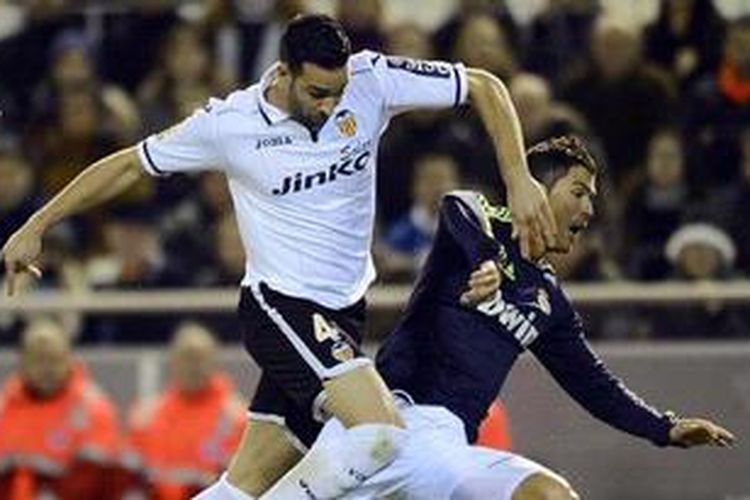 Bintang Real Madrid, Cristiano Ronaldo, terjatuh saat berebut bola dengan bek Valencia, Adil Rami, dalam pertandingan lanjutan liga BBVA, Minggu atau Senin (21/1/2013) dini hari WIB.  