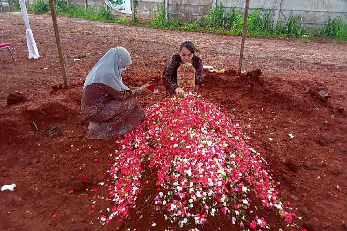 Istri Hilman Dewi Natalia memegang papan nisan bersama Asma Nadia