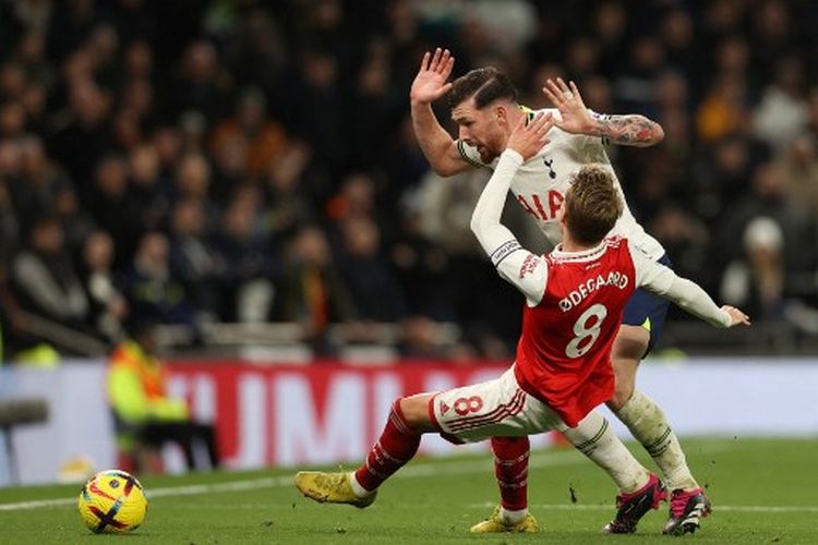 Hasil Tottenham vs Arsenal: Pierre Hojbjerg (belakang) berduel dengan Martin Odegaard (terjatuh) pada pertengahan laga penutup pekan ke-20 Liga Inggris yang mempertemukan Tottenham vs Arsenal, Minggu (15/1/2023). Arsenal selaku tim tamu sukses membungkam Tottenham 2-0.