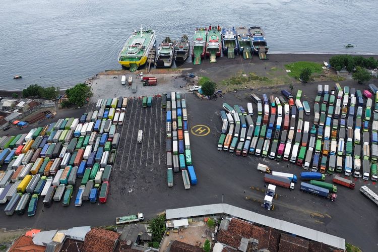 Foto udara antrean truk pengangkut logistik menunggu giliran memasuki kapal di Pelabuhan Bulusan, Ketapang, Banyuwangi, Jawa Timur, Jumat (25/7/2025). Untuk mengurai kemacetan kendaraan bertonasi besar yang mencapai 31 kilometer, PT ASDP Indonesia Ferry menambah satu armada kapal yakni KMP Gading Nusantara yang mampu mengangkut 20-30 truk dalam satu kali penyeberangan menuju Pelabuhan Gilimanuk, Bali. ANTARA FOTO/Budi Candra Setya/tom.