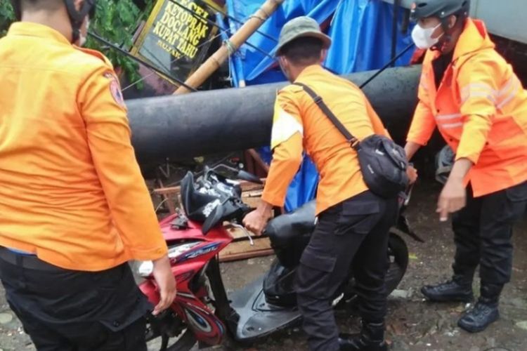 Petugas tengah evakuasi motor warga yang tertimpa papan reklame yang berada di Jalan Raya Ciluar, Desa Pasirlaja, Kecamatan Sukaraja, Kabupaten Bogor, Jawa Barat, setelah diterjang angin kencang pada Kamis (10/3/2022) sore.