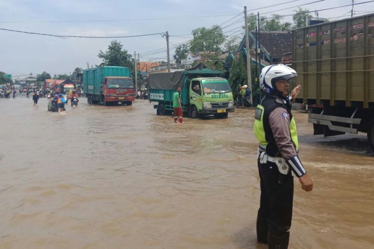 Polisi bersama warga membuka kembali jalur pantura di Kecamatan Kraton Kabupaten Pasuruan yang sebelumnya lumpuh akibat genangan air dari luapan Sungai Welang.