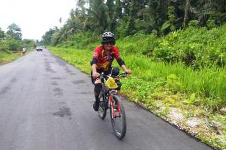 Om Kim, salah seorang peserta Jelajah Sepeda Papua, saat menempuh etape antara Sarmi dengan Bonggo, Rabu (3/6/2015).