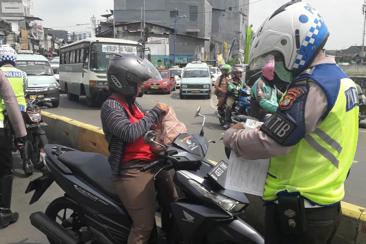 Seorang pengendara sepeda motor ditilang polisi karena menerobos jalur transjakarta di Jalan Jatinegara Barat, Rabu (20/3/2019).
