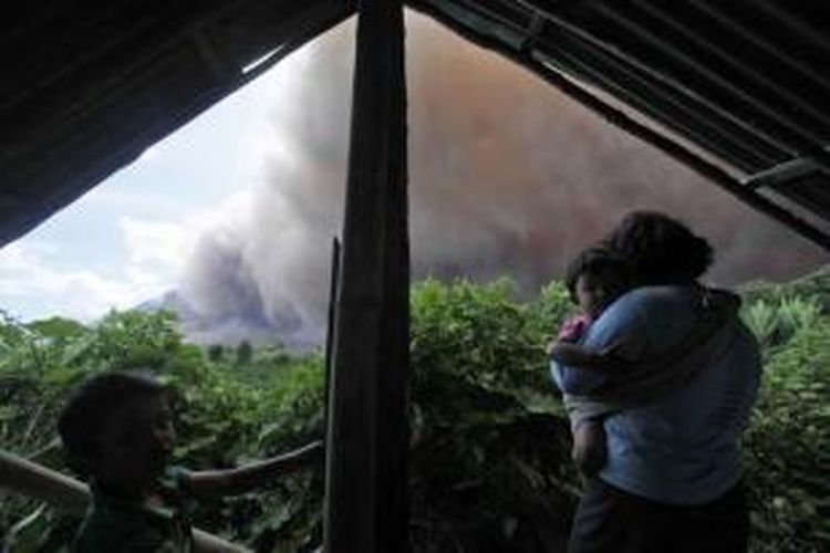 Seorang perempuan dan anaknya tak jauh dari erupsu Gunung Sinabung di Desa Tiga Kicat, Karo, Sumut, 13 Juni 2015.