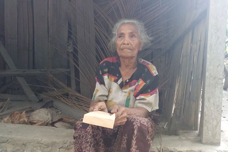 Nenek Paulina Poing (79), warga Dusun Gehak Reta, Desa Koting D, Kecamatan Koting, Kabupaten Sikka, Flores, Nusa Tenggara Timur, duduk di depan gubuknya sambil memegang amplop berisi uang dari Presiden Joko Widodo, Minggu (20/10/2019).