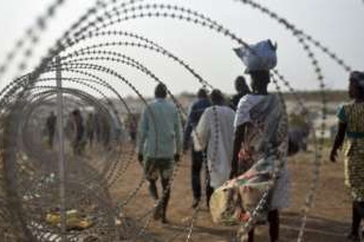 Warga berjalan di sisi pagar berduri di pangkalan PBB di Juba, Sudan Selatan