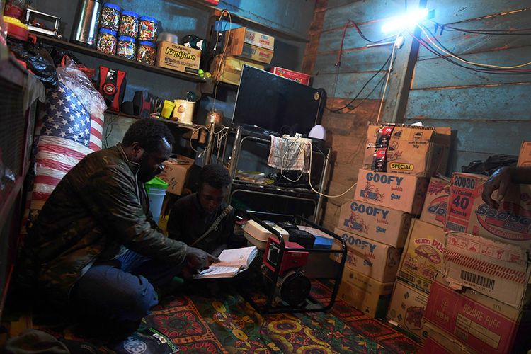 Warga menemani anaknya belajar dengan penerangan lampu dari genset di Kampung Obano, Distrik Paniai Barat, Papua, Kamis (29/11/2018). 